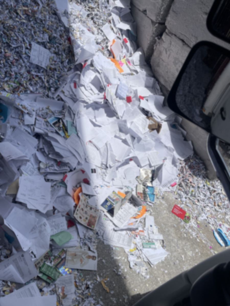 Unshredded paper records dumped on the ground at a recycling yard